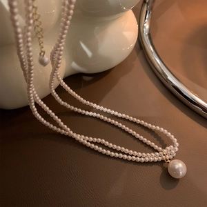 Elegante doppellagige 14k Gold Perlenkette mit großem Rundanhänger auf Ledergrund