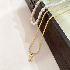 Detailopname van de gouden slangenketting met een minimalistische hanger met de letter Z