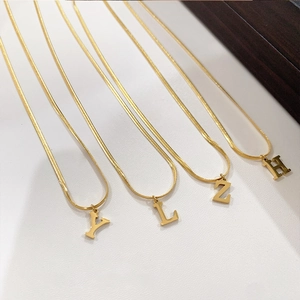 Detail macro-opname van vier gouden slangenkettingen met 3D hoofdletter hangers
