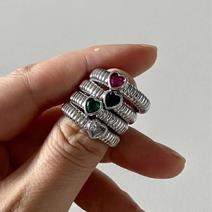 Nahaufnahme von vier bunten herzförmigen Zirkonia-Ringen mit gedrehtem Silberband-Design