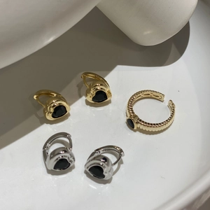 Detail von Herz-Ohrringen und strukturiertem Goldring mit schwarzen Zirkon-Einlagen