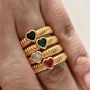 Vier goldene Spiralringe mit bunten herzförmigen Zirkonia am Finger getragen