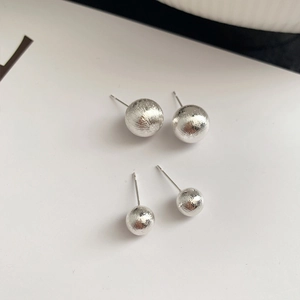 Brushed silver metal ball earrings in two sizes on a white background minimalist style