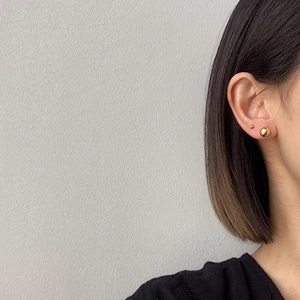 Close-up of minimalist gold ball stud earrings worn by a model in a side view profile