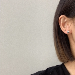 Minimalist silver spherical stud earring shown on model with brushed metal finish