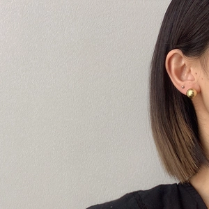Minimalist golden ball stud earrings shown on model for a sleek metallic fashion look