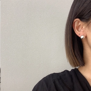 Close-up of minimalist brushed silver sphere stud earrings worn on ear for style