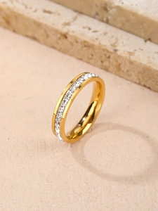 Detailed close-up of golden eternity band ring with square zircon stones on stone base