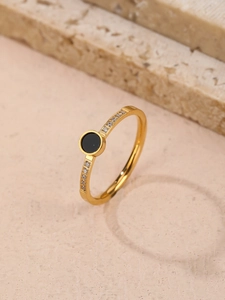 Close-up of gold titanium ring featuring a black circular inlay and micro-pave crystals