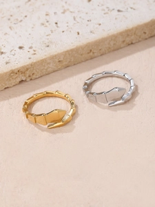 Dettaglio di anelli a serpente in oro e argento con texture geometrica su pietra