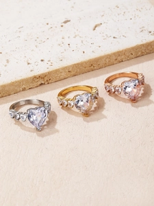 Detailansicht von Herz-Zirkonia-Ringen in Silber, Gold und Roségold auf Steinplatte