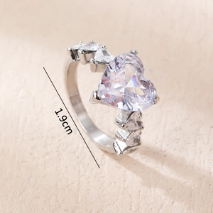 Romantischer Silberring mit Herz-Zirkonia auf beigem Leder im minimalistischen Design