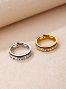 Vista macro de anillos oro y plata con líneas negras y pavé de circonitas cúbicas