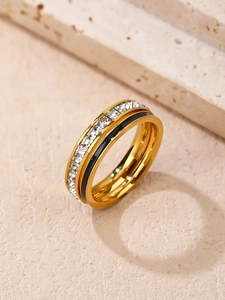 Detalle de anillo dorado con piedras de circonita cuadrada e incrustación de esmalte negro