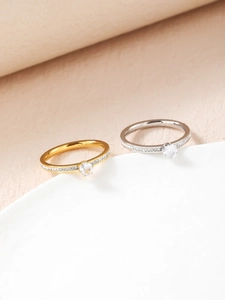 Primo piano di anelli a sei griffe in oro e argento con zirconi su espositore bianco