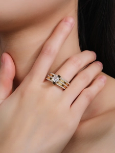 Gros plan d'une bague trois couches en métal bicolore avec zircon central sur le doigt