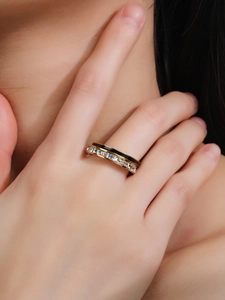 Detalle de anillo dorado de doble capa con esmalte negro y piedras de circón cuadradas