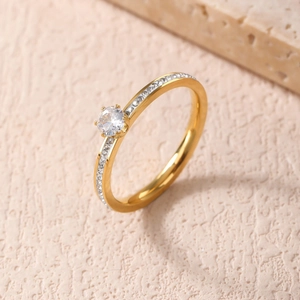 Anello elegante placcato oro con piccole pietre laterali e uno zircone tondo a quattro griffe