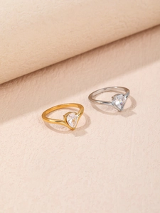 Detailed view of pear-cut zircon rings in 18K gold and silver finishes on textured base