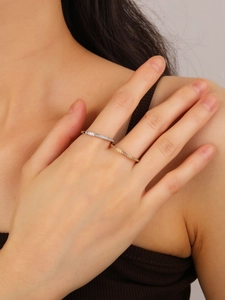 Macro shot of silver and gold thin titanium rings with pavé diamonds on model hand