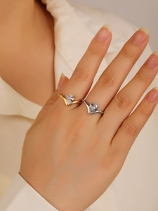 Close-up of gold and silver curved rings with pear-shaped zircon on a finger