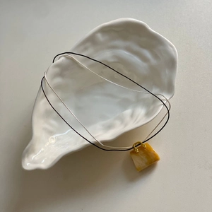 Dettaglio del pendente in pietra naturale a forma di borsa su una collana a due strati