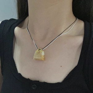 Collana con ciondolo a borsa in pietra giallo chiaro su cordino nero e bianco a strati