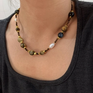 Collana con occhio di tigre e perle d'acqua dolce indossata sul collo alla moda