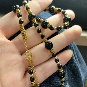 Dettaglio della collana con occhio di tigre e onice nera con chiusura a moschettone dorata