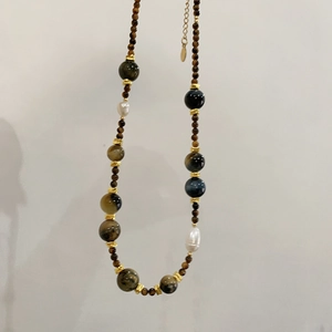 Dettaglio della collana in occhio di tigre e perle con distanziatori dorati e catena di estensione