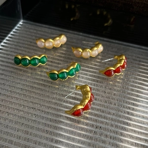 Detalle de pendientes vintage con forma de vaina y piedras de colores rosa verde y rojo