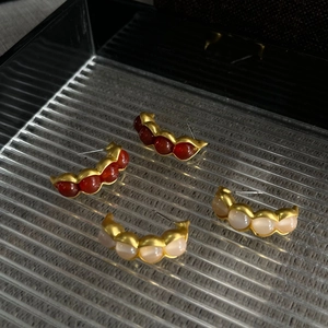 Primer plano de dos pares de pendientes de vaina vintage dorados con piedras rojas y rosas