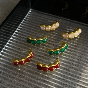 Detalle de pendientes vintage en forma de vaina con piedras de colores en bandeja