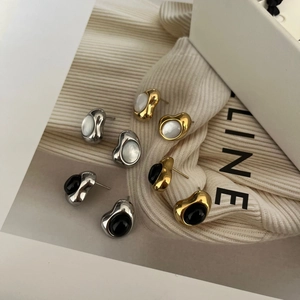 Detalle macro de pendientes de frijol irregulares en oro y plata con incrustación de nácar