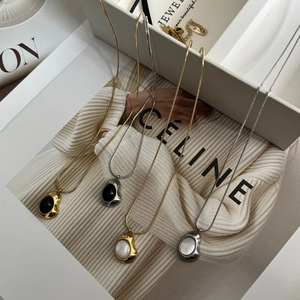 Detalle de collares de acero de titanio de estilo francés con colgantes de nácar blanco y negro