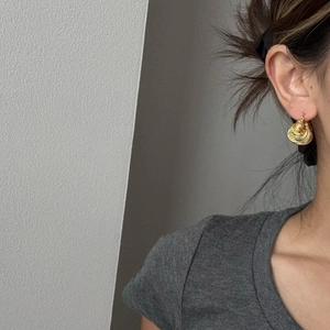 Dettaglio di orecchini a cerchio in ottone placcato oro 18K con texture a spirale su modella