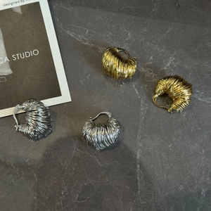Dettaglio macro di orecchini a cerchio a U in oro e argento con texture a spirale