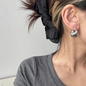 Orecchini a cerchio argentati a forma di corno con trama a pieghe indossati da una modella
