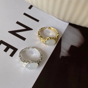 Detail view of hammered gold and silver feather rings with white cat eye stones