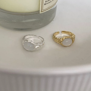 Macro detail of brass feather rings with white cat eye stone on a white display tray