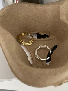 Macro shot of gold and silver feather-textured adjustable rings in a rustic box