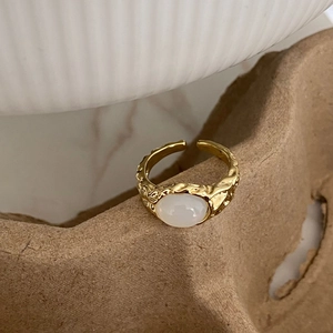 Close-up of gold-plated feather ring with white cat eye stone and hammer texture details