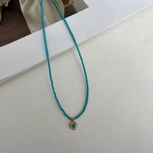 Nahaufnahme der türkisfarbenen Perlen und des goldenen Herzanhängers im Vintage-Stil