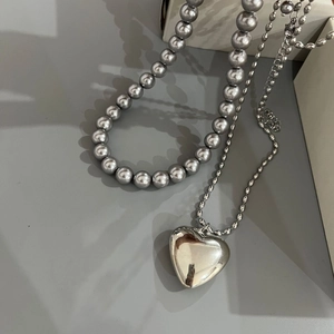 Detailed view of large silver heart pendant on bead chain with grey pearl necklace