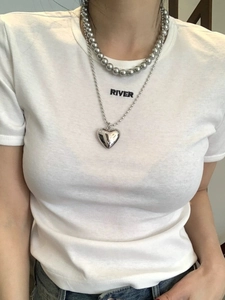 Detail of silver beaded necklace and polished heart pendant on white t-shirt model