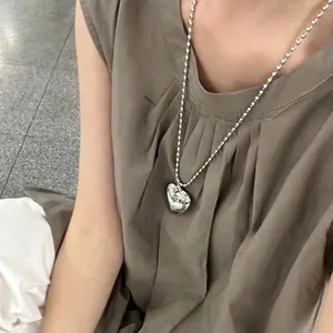 Silver hollow heart pendant necklace with beaded chain on female model in casual style