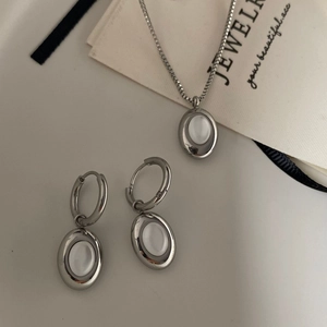 Detail view of oval white shell jewelry set with necklace and earrings on a gift bag
