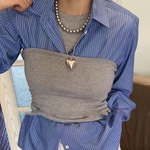 Gray pearl necklace with hollow heart pendant worn over a blue striped shirt