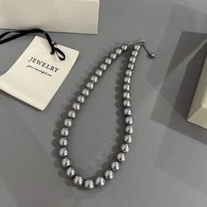 Close-up of gray faux pearl necklace with silver lobster clasp and adjustable metal chain