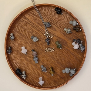 Assorted natural stone mushroom pendants and gold beads arranged in a wooden tray